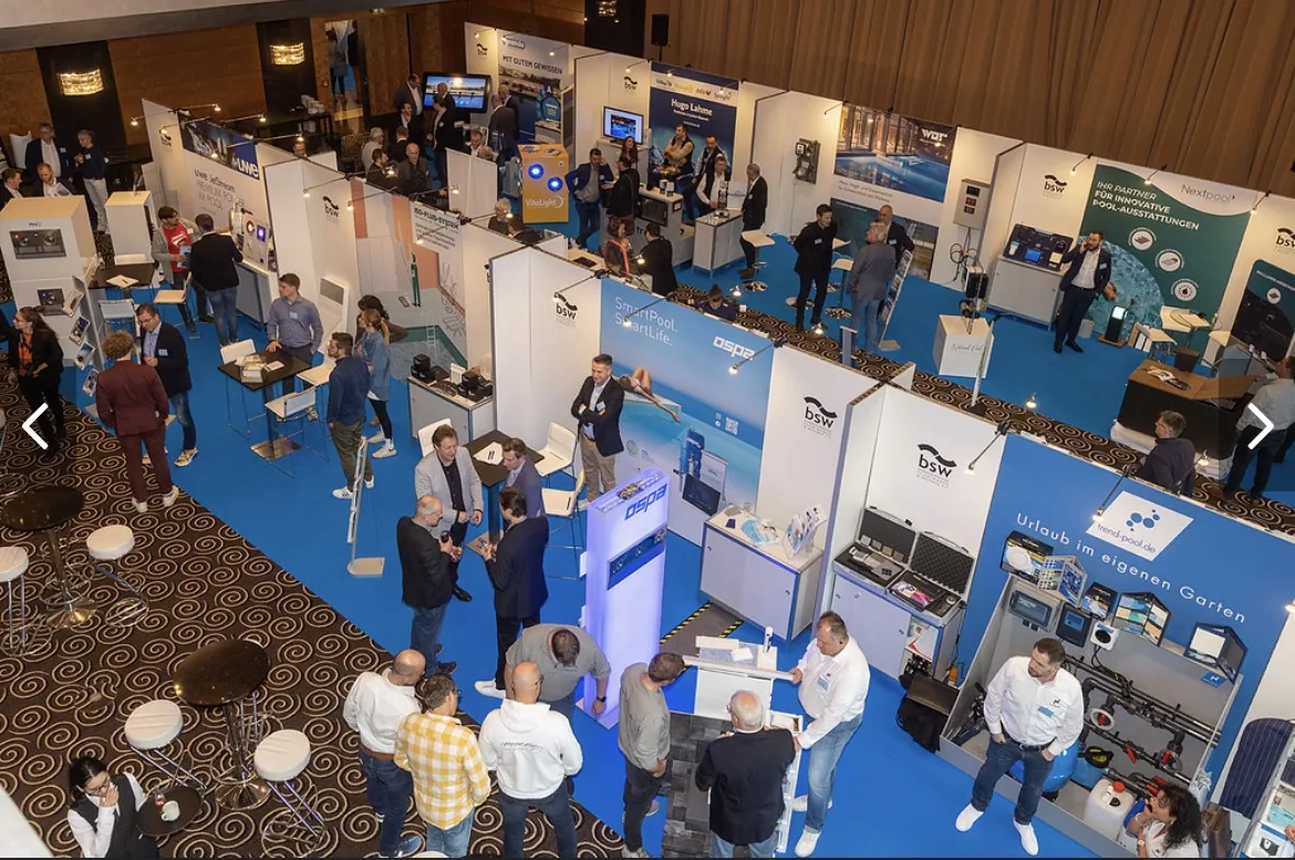 Übersicht einer Fachmesse mit Messeständen und blauen Teppichflächen